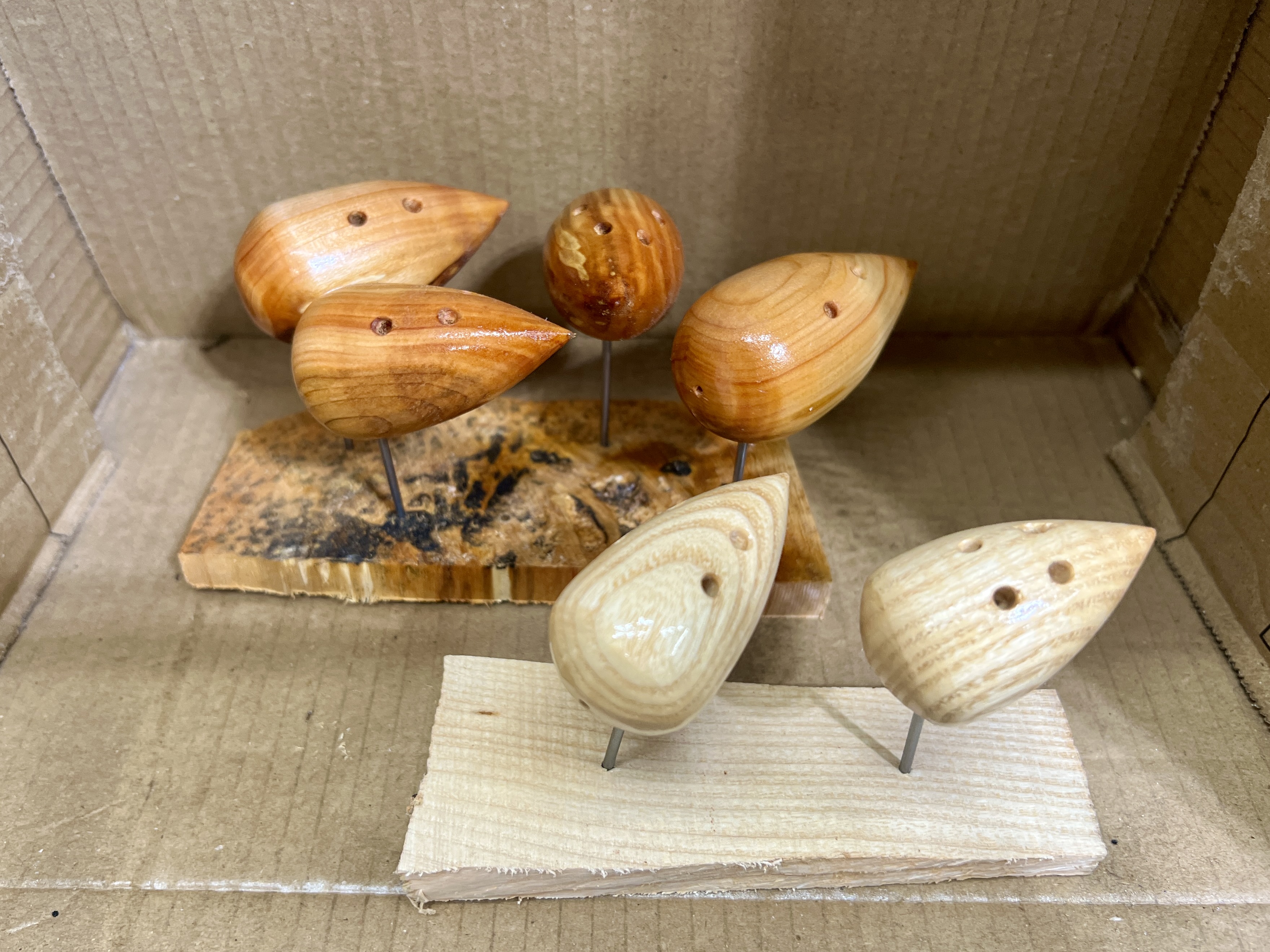 Several turned wooden mouse bodies drying on a clamp after being lacquered
